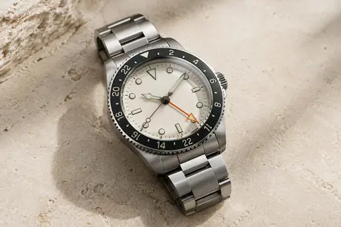 Montre GMT automatique à cadran clair, aiguille orange, repères luminescents et bracelet en acier
